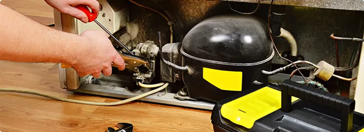 Refrigerator repair technician fixing the compressor and wiring in Venice, IL